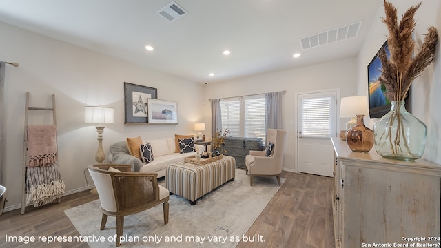 living area with wood finished floors, visible vents, and recessed lighting