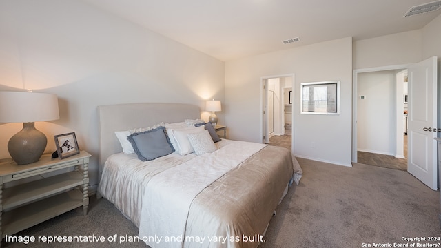 carpeted bedroom with visible vents and ensuite bathroom