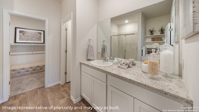 full bath with baseboards, wood finished floors, vanity, and a stall shower