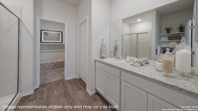 bathroom with baseboards, vanity, wood finished floors, and a shower stall