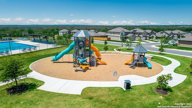 communal playground featuring a yard and a residential view