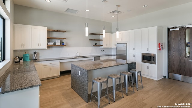 kitchen with light wood-style flooring, open shelves, visible vents, appliances with stainless steel finishes, and a sink