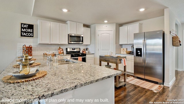 kitchen featuring light stone counters, white cabinets, appliances with stainless steel finishes, and a sink