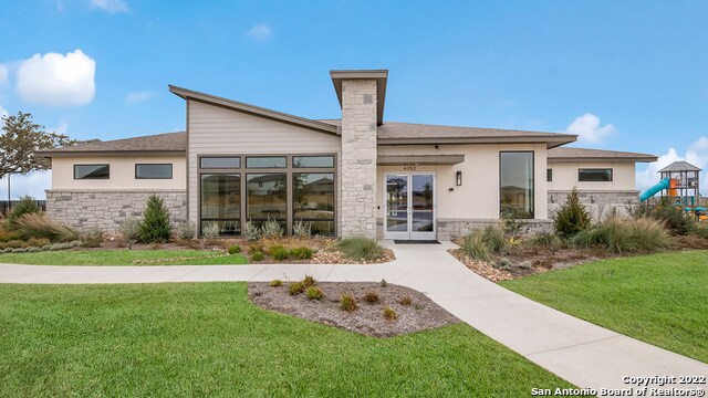 14614 Clay Ridge Run, San Antonio, TX 78253 - back of property with stone siding, a lawn, stucco siding, and a playground