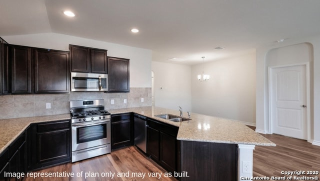 14614 Clay Ridge Run, San Antonio, TX 78253 - kitchen featuring appliances with stainless steel finishes, a sink, wood finished floors, a peninsula, and light stone counters