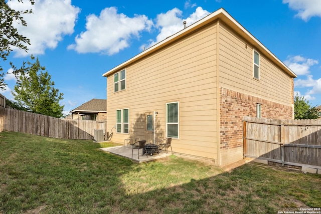 back of house with brick siding, a yard, a fenced backyard, and a patio