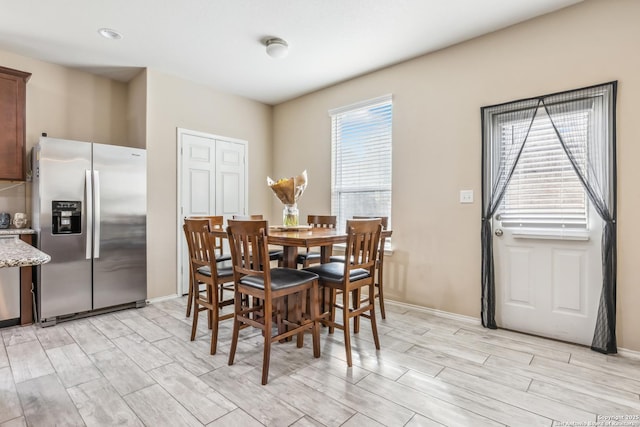dining area featuring baseboards and wood tiled floor