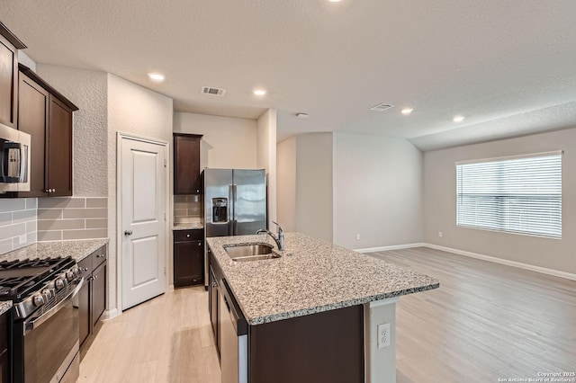 5680 Jasmine Spur, Bulverde, TX 78163 - kitchen featuring stainless steel appliances, light wood-style flooring, a kitchen island with sink, a sink, and dark brown cabinets
