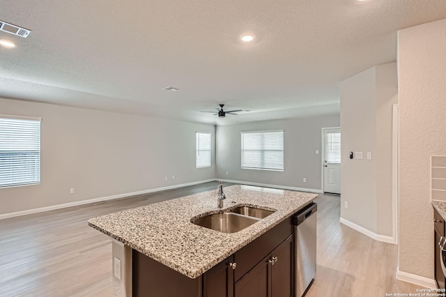 5680 Jasmine Spur, Bulverde, TX 78163 - kitchen featuring a sink, open floor plan, stainless steel dishwasher, light wood finished floors, and a textured ceiling
