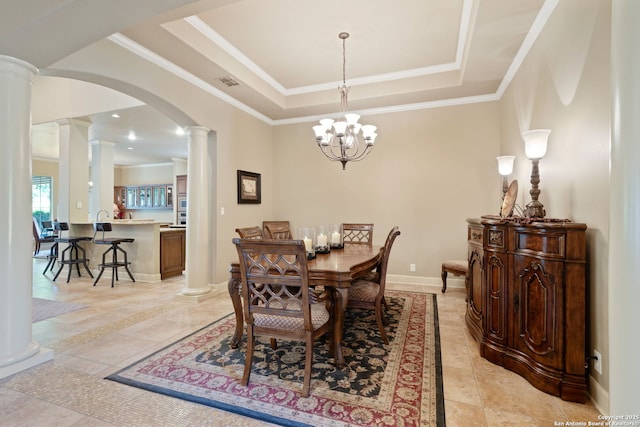 dining space with arched walkways, a tray ceiling, ornamental molding, visible vents, and ornate columns