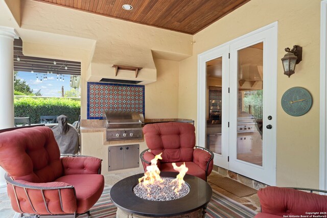 view of patio with a fire pit, exterior kitchen, and area for grilling