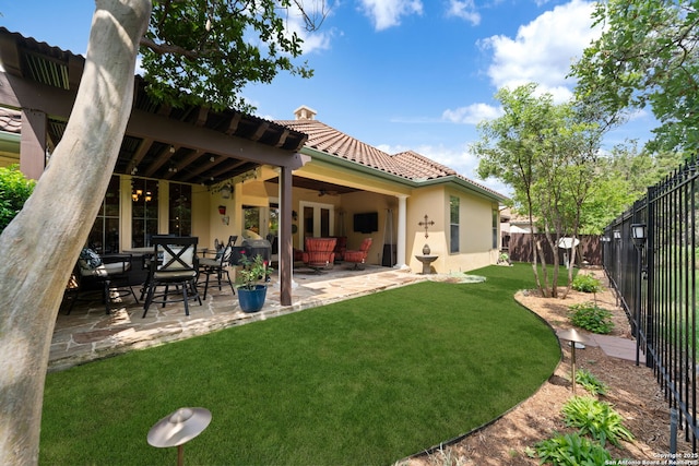 back of house featuring a tile roof, a fenced backyard, a ceiling fan, a yard, and stucco siding