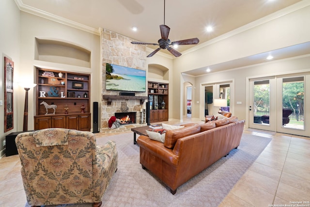 living room with a ceiling fan, ornamental molding, light tile patterned floors, a fireplace, and built in shelves