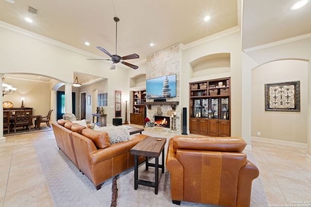 living room featuring a stone fireplace, crown molding, and built in shelves