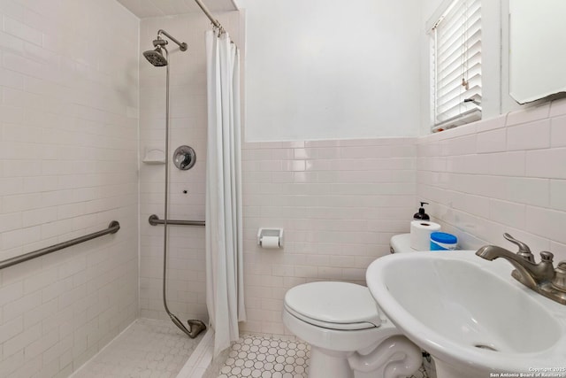 bathroom featuring tile patterned floors, toilet, a sink, tile walls, and a stall shower