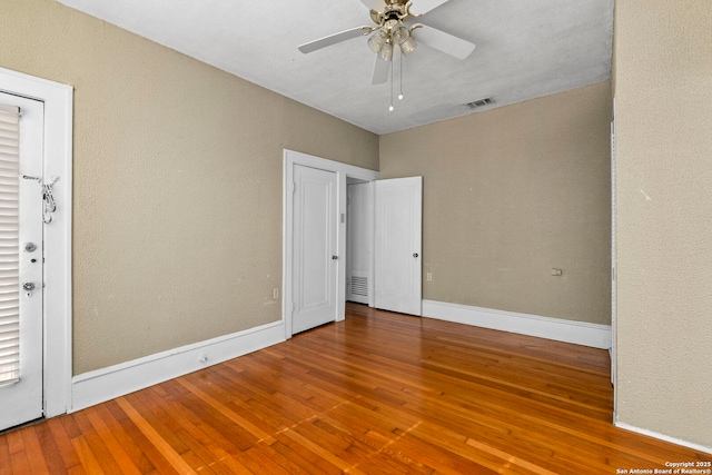 unfurnished bedroom featuring baseboards, hardwood / wood-style flooring, visible vents, and ceiling fan