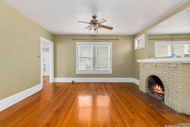 unfurnished living room featuring baseboards, a fireplace, ceiling fan, and wood-type flooring