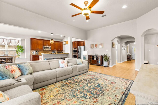 living area with ceiling fan, arched walkways, baseboards, visible vents, and recessed lighting