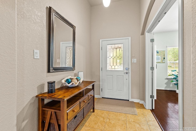 entryway featuring a textured wall and baseboards