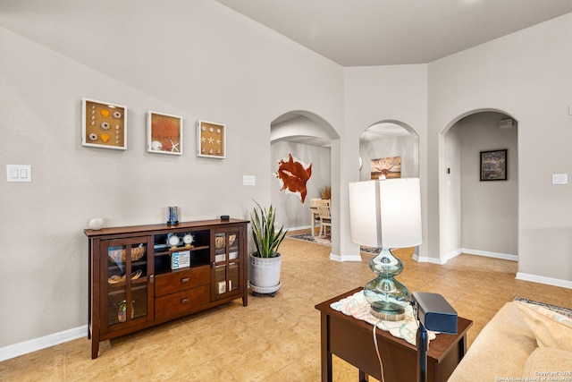 living area featuring baseboards, arched walkways, and light tile patterned floors