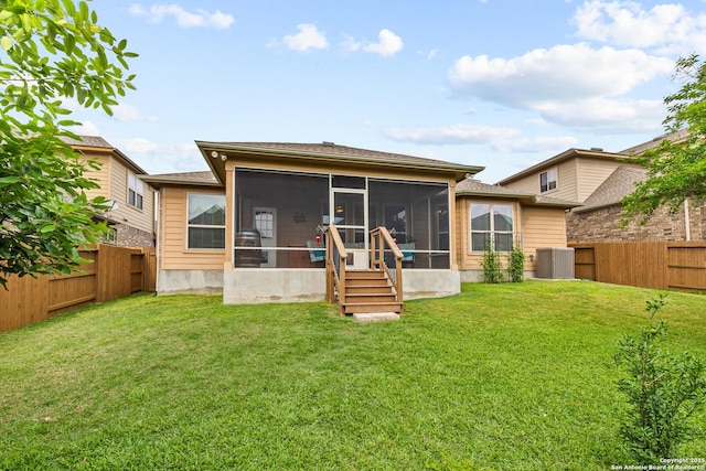 rear view of house with a fenced backyard, a sunroom, a yard, and cooling unit