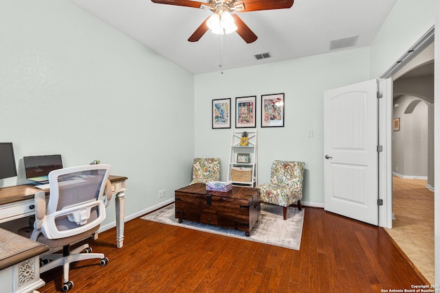 office with wood finished floors, visible vents, arched walkways, and ceiling fan