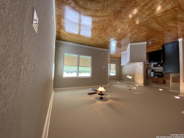 unfurnished living room with baseboards, crown molding, and carpet floors