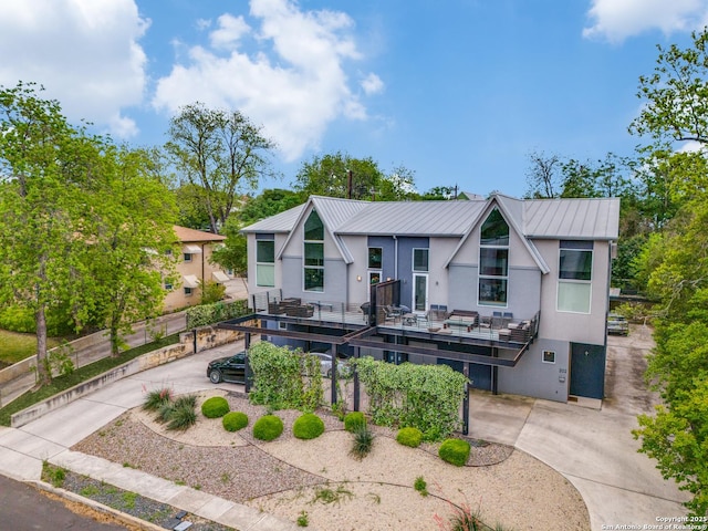 view of front of property featuring stucco siding, a wooden deck, a standing seam roof, and metal roof
