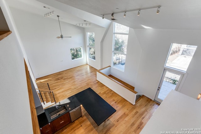 entryway featuring a ceiling fan, a towering ceiling, light wood-style floors, and rail lighting