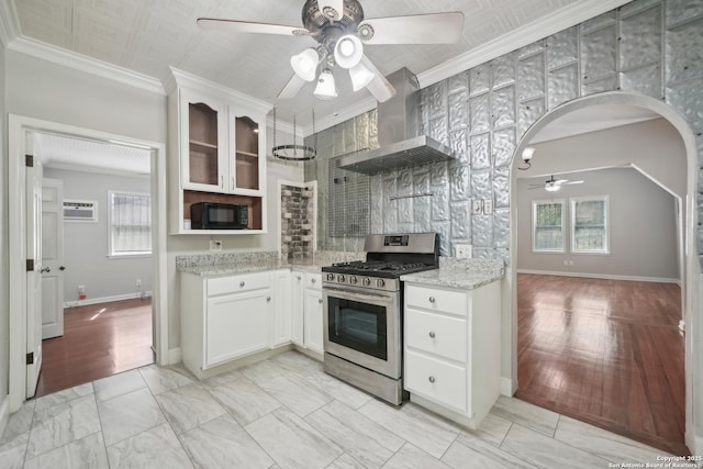 1923 W Pyron Ave, San Antonio, TX 78211 - kitchen with arched walkways, ceiling fan, gas stove, black microwave, and wall chimney exhaust hood