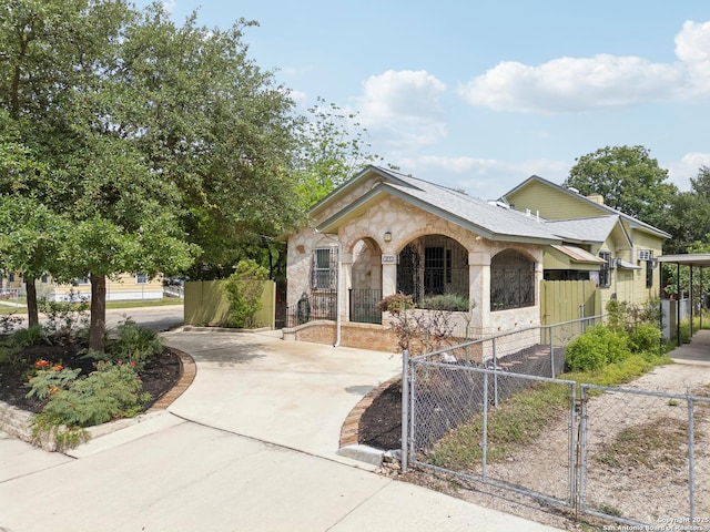 1923 W Pyron Ave, San Antonio, TX 78211 - view of front of property featuring driveway, a gate, a fenced front yard, and stone siding
