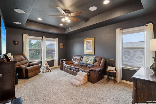 carpeted living area featuring recessed lighting, a raised ceiling, a ceiling fan, and baseboards