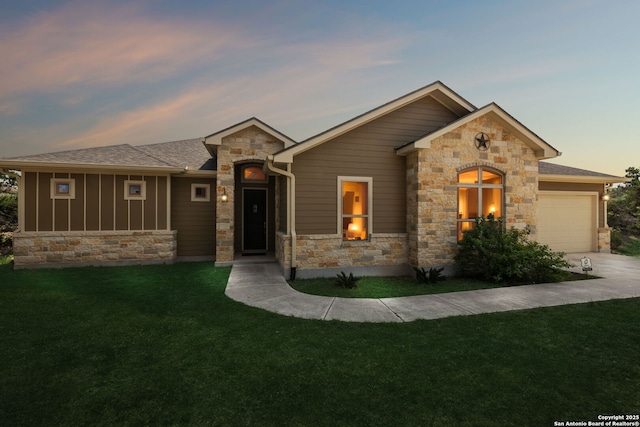 view of front facade featuring driveway, stone siding, board and batten siding, a yard, and a garage