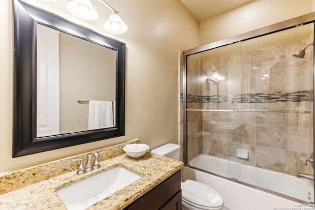 bathroom featuring vanity, enclosed tub / shower combo, and toilet