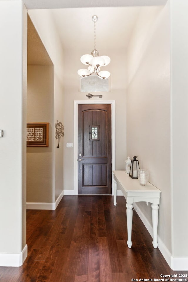 entryway with baseboards, wood finished floors, and a chandelier