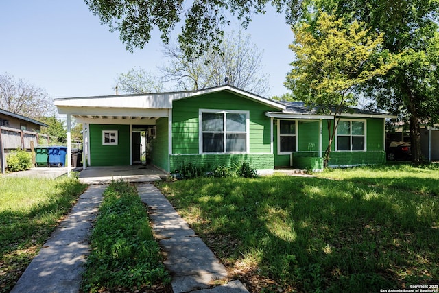 ranch-style home featuring a front lawn, an attached carport, and driveway