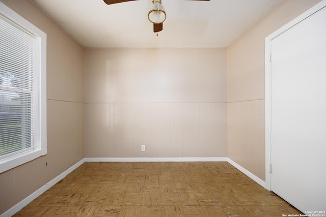 spare room with wainscoting, baseboards, and ceiling fan