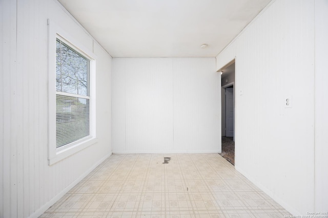 interior space with tile patterned floors, baseboards, and wood walls