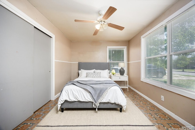 bedroom with a ceiling fan, baseboards, a closet, and multiple windows