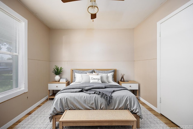 bedroom featuring wainscoting, multiple windows, and wood finished floors
