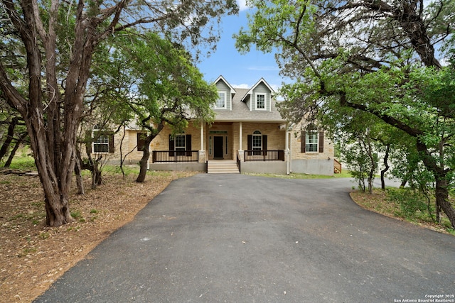 view of front facade featuring aphalt driveway, covered porch, and brick siding