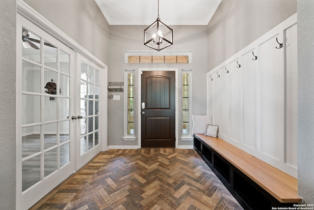 mudroom with plenty of natural light, a towering ceiling, a chandelier, and ornamental molding