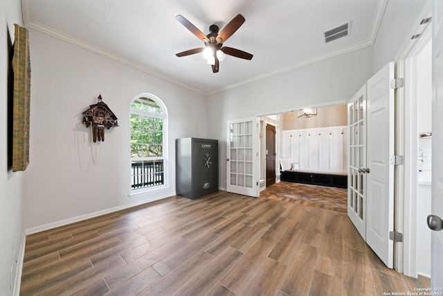 spare room featuring crown molding, wood finished floors, ceiling fan, baseboards, and visible vents