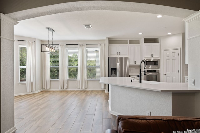 kitchen featuring a peninsula, a sink, visible vents, a notable chandelier, and appliances with stainless steel finishes