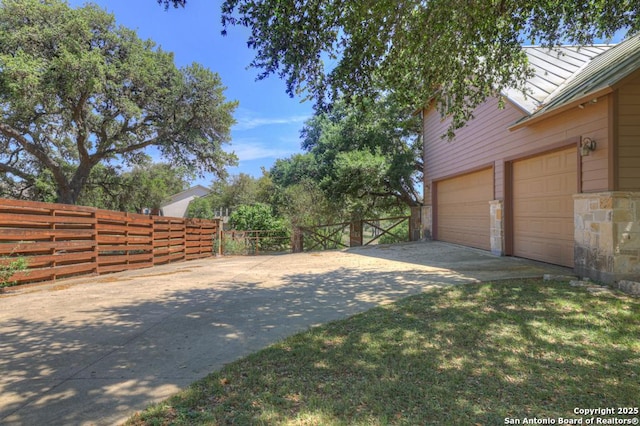 view of yard with fence, driveway, and a garage