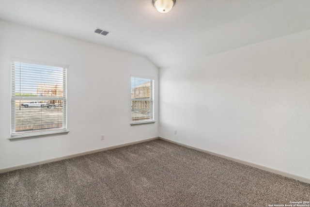 carpeted empty room with vaulted ceiling, visible vents, and baseboards
