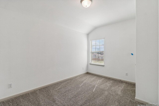 unfurnished room with vaulted ceiling, baseboards, and light colored carpet