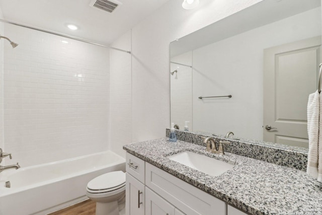 bathroom with wood finished floors, visible vents, toilet, vanity, and  shower combination
