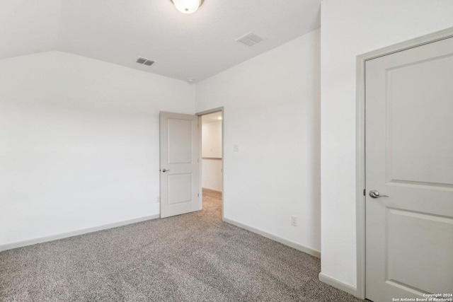 unfurnished bedroom featuring carpet, visible vents, lofted ceiling, and baseboards