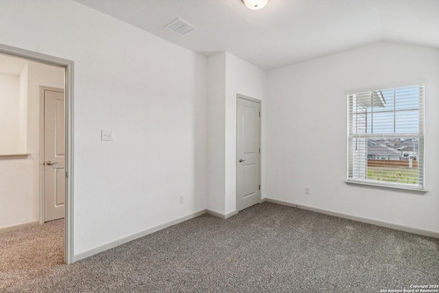 unfurnished bedroom with baseboards, carpet flooring, vaulted ceiling, and visible vents